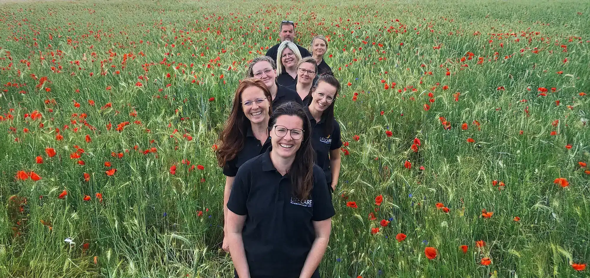 Das Team von LifeCare Wundmanagement auf einer blühenden Wiese.